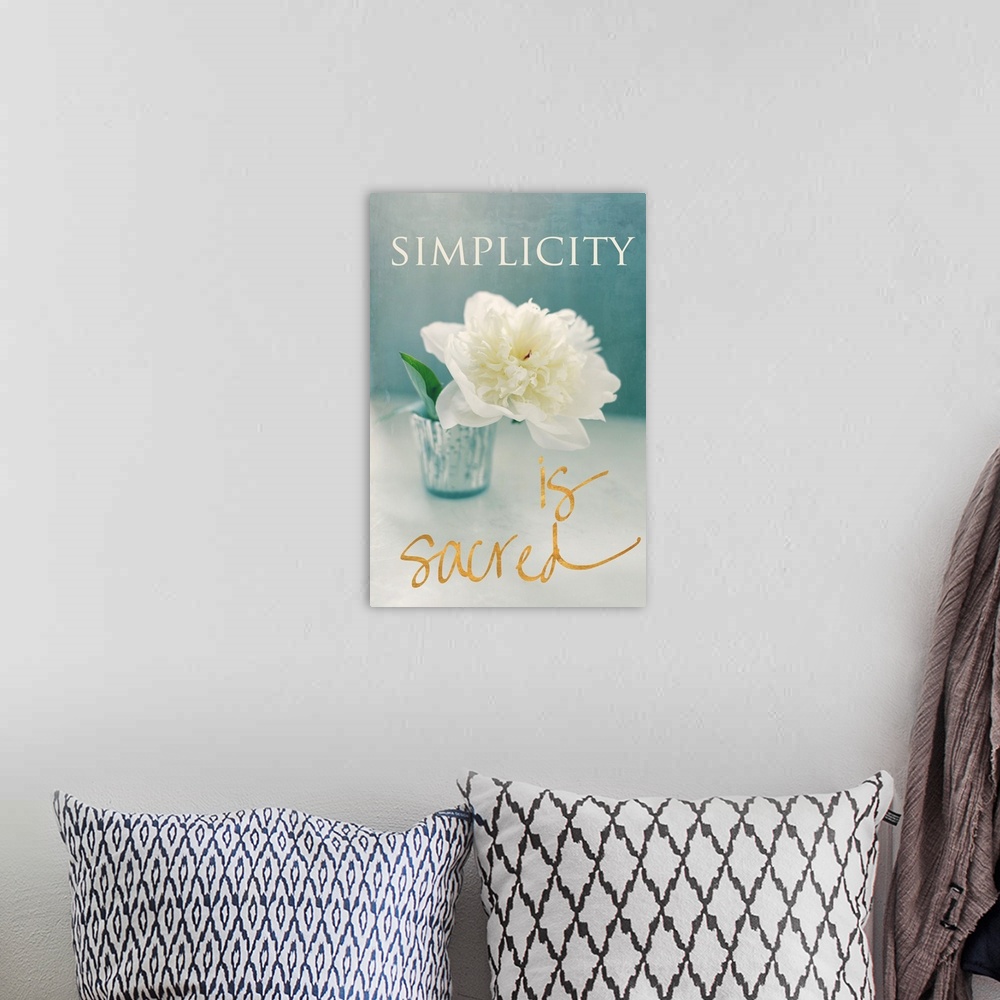 A bohemian room featuring Photograph of a big white flower in a vase with the phrase "Simplicity is sacred" written around ...