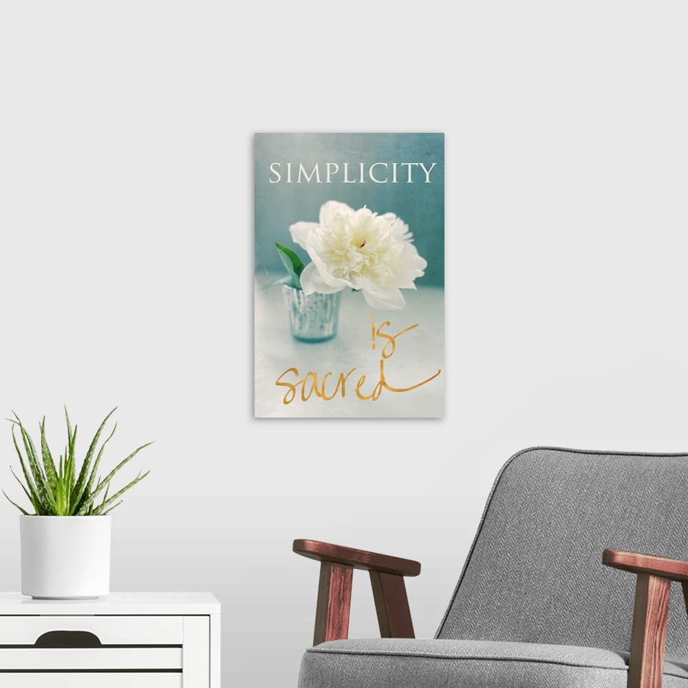 A modern room featuring Photograph of a big white flower in a vase with the phrase "Simplicity is sacred" written around ...
