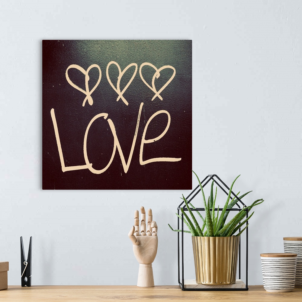 A bohemian room featuring The word "Love" with three little hearts above written on a dark surface.