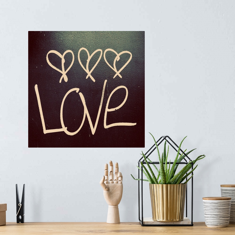 A bohemian room featuring The word "Love" with three little hearts above written on a dark surface.