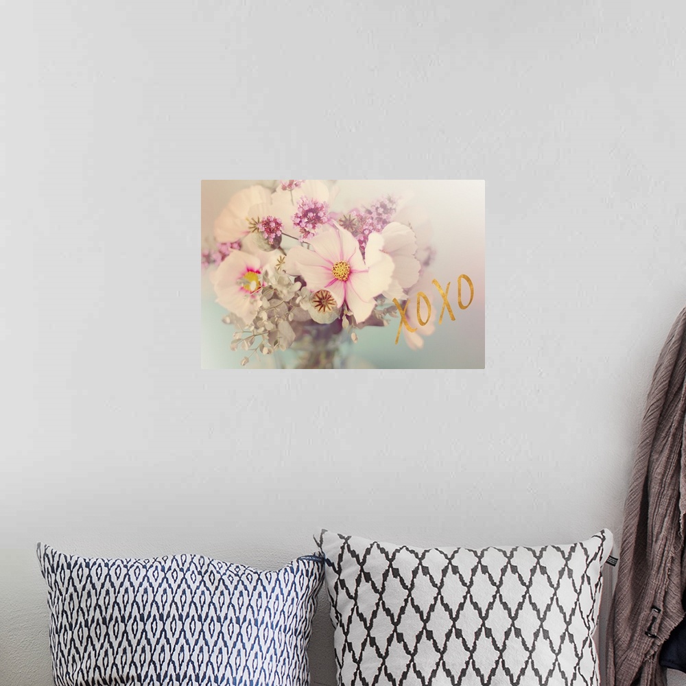 A bohemian room featuring Soft, pink toned photograph of flowers arranged in a vase with "XOXO" written in gold on the side.