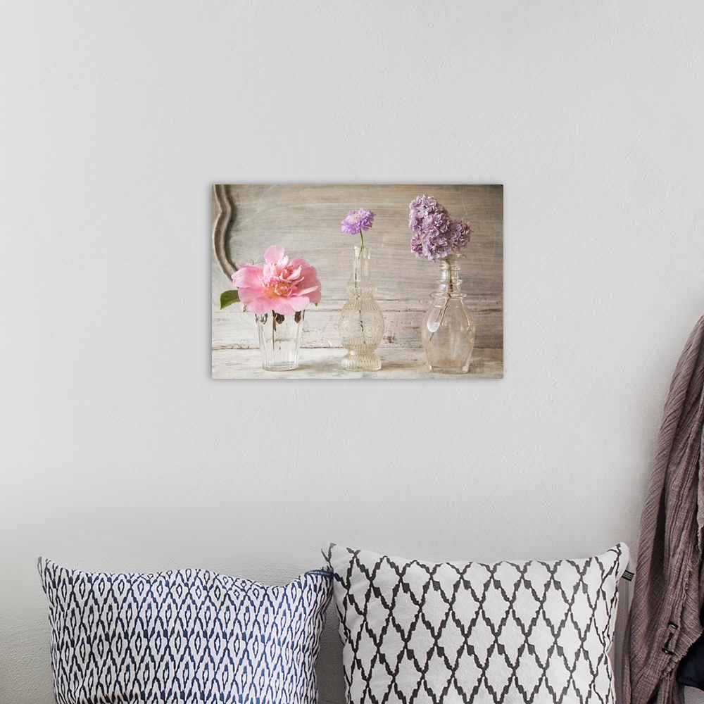 A bohemian room featuring Photograph of different flowers in a small glass vases, against a vintage wall.