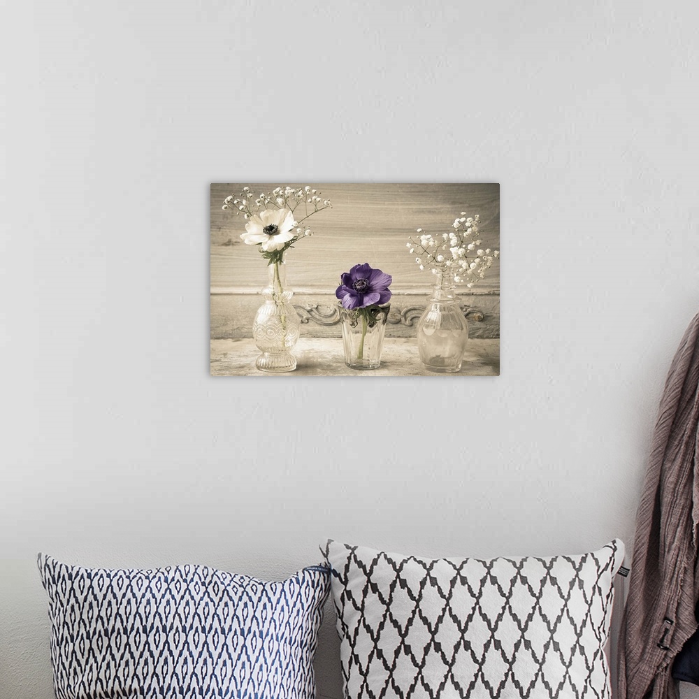 A bohemian room featuring Photograph of different flowers in a small glass vases, against a vintage wall.