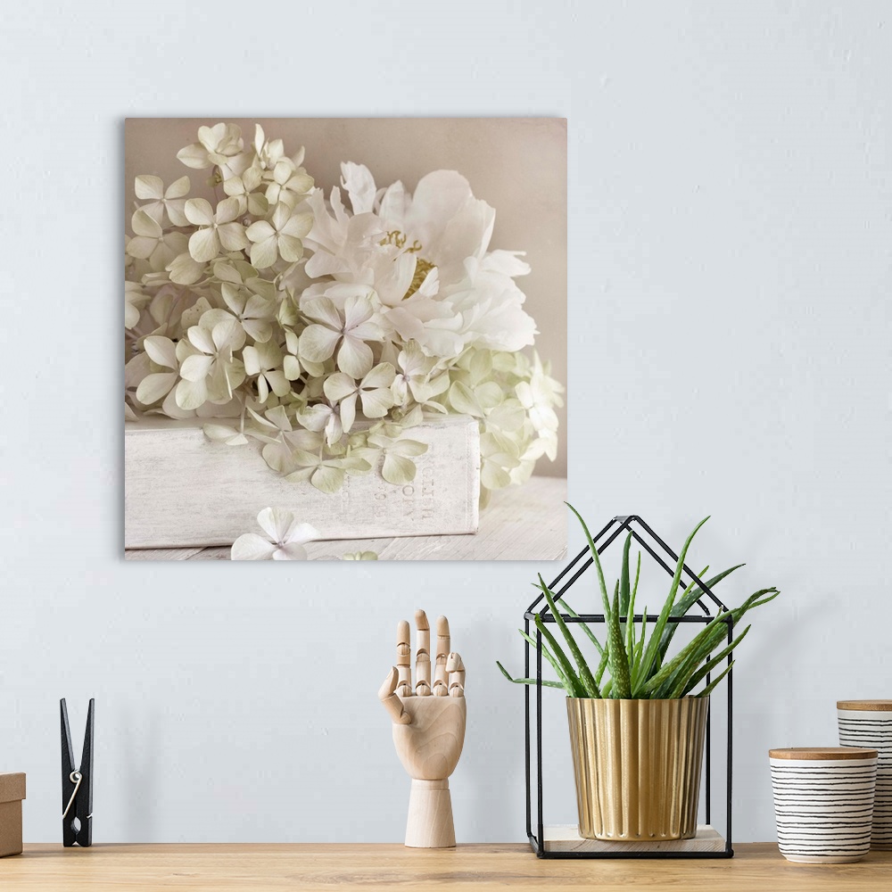 A bohemian room featuring Square photo on canvas of white flowers laying on top of a white book with the spine facing the c...