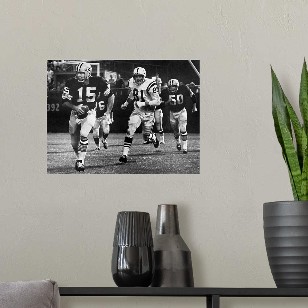 A modern room featuring Quarterback Bart Starr of the Green Bay Packers attempting to run for a first down against the Ba...
