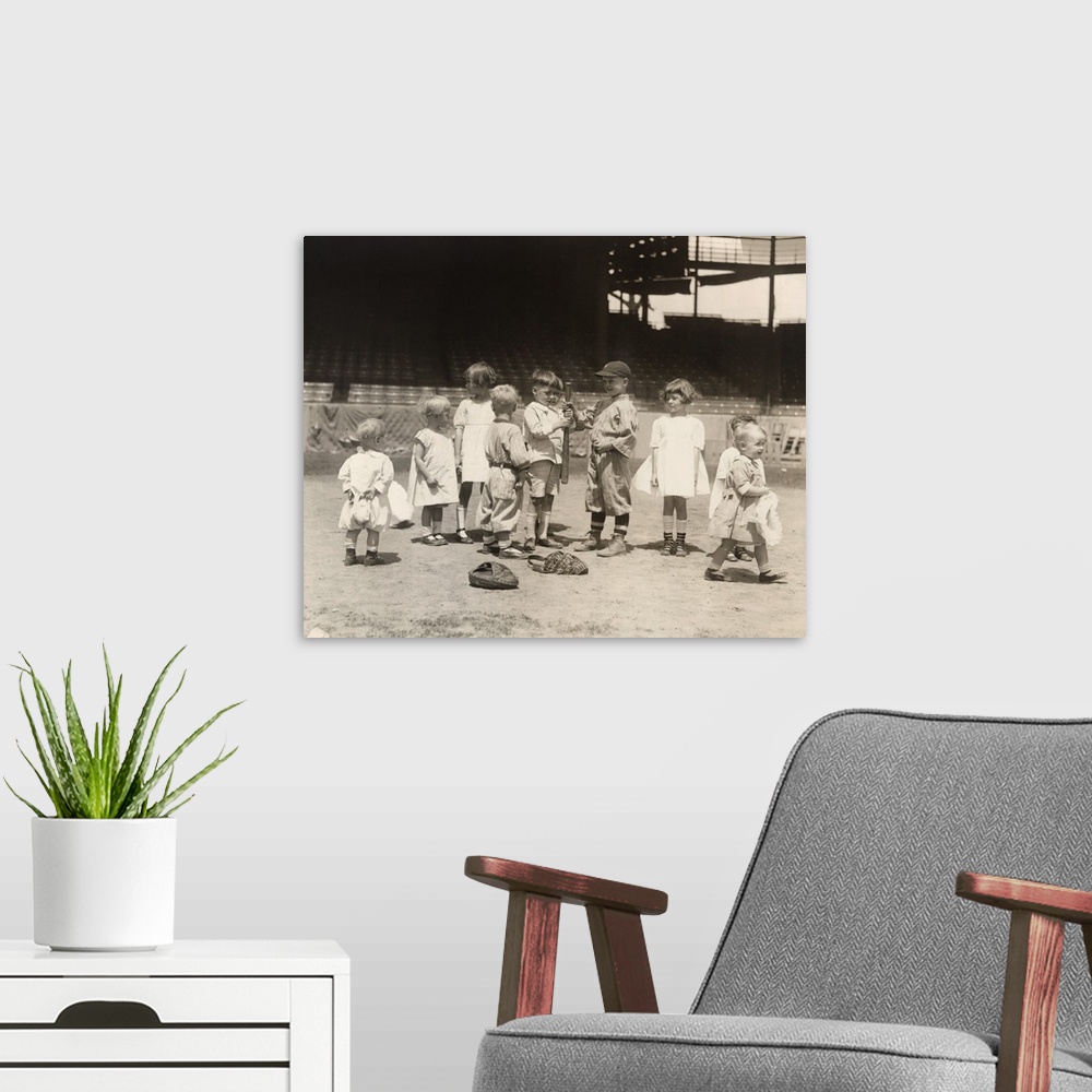 A modern room featuring Young boys and girls on a baseball field at a major league stadium. Photograph, early 20th century.