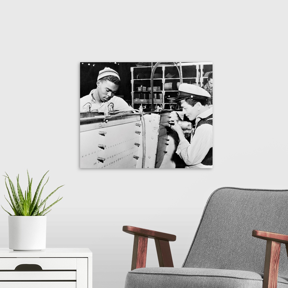 A modern room featuring An African-American man and an Asian-American man at work at the Douglas Aircraft Company factory...