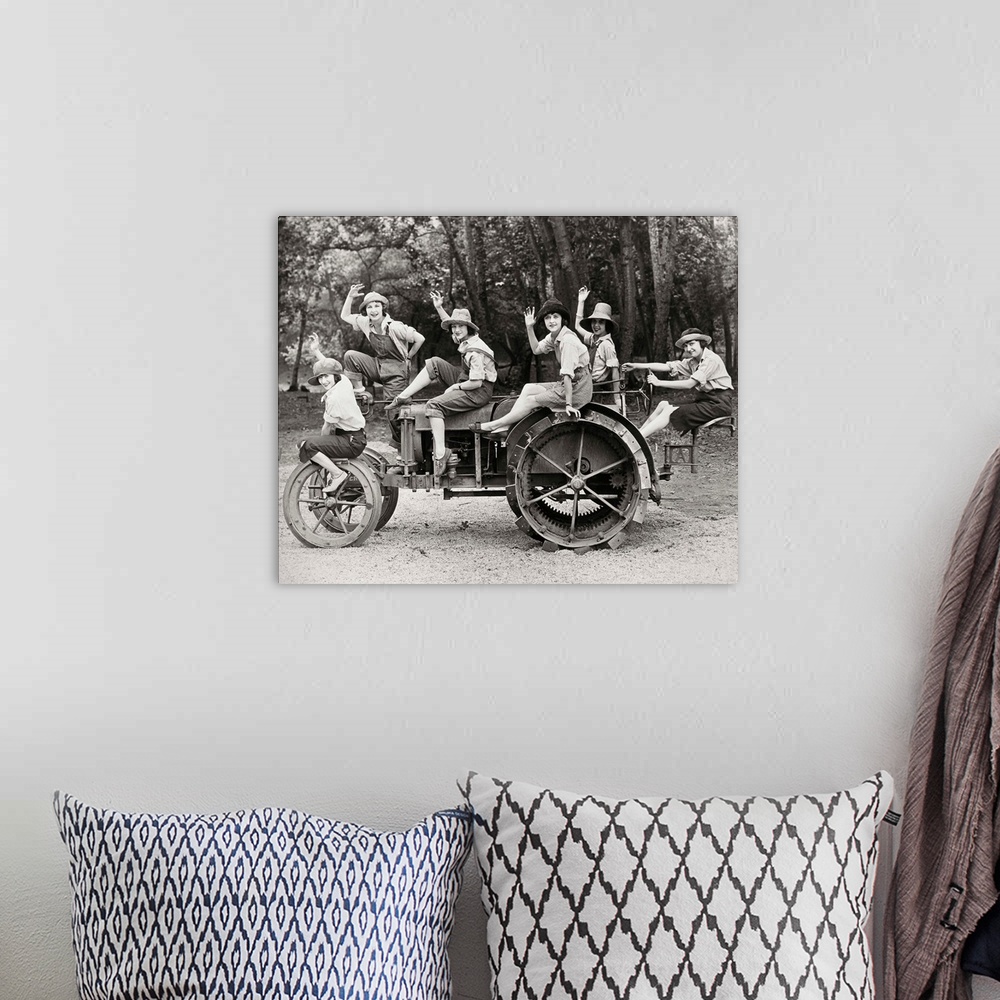 A bohemian room featuring A group of women posing on a tractor in rural America. Photograph, c1925.