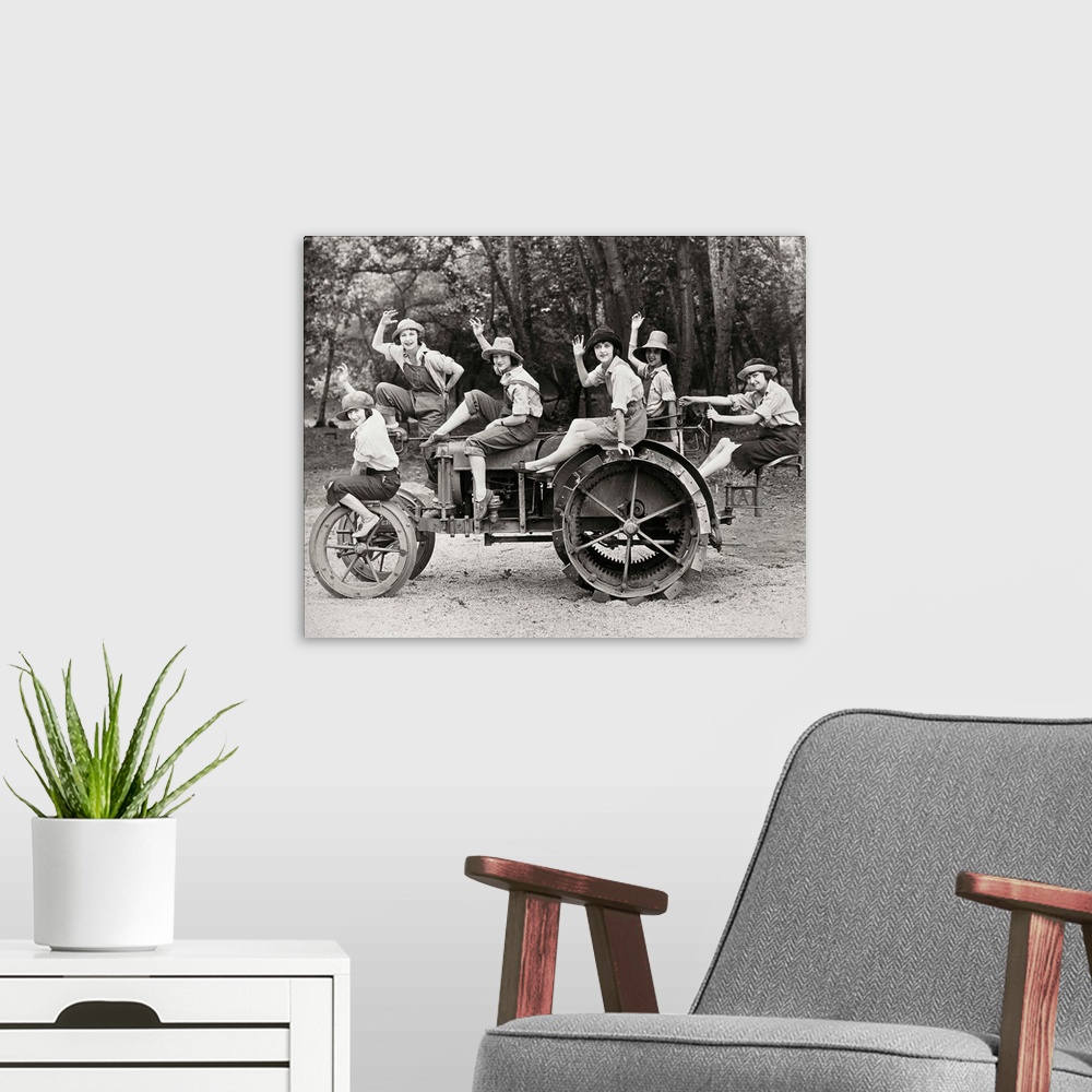 A modern room featuring A group of women posing on a tractor in rural America. Photograph, c1925.