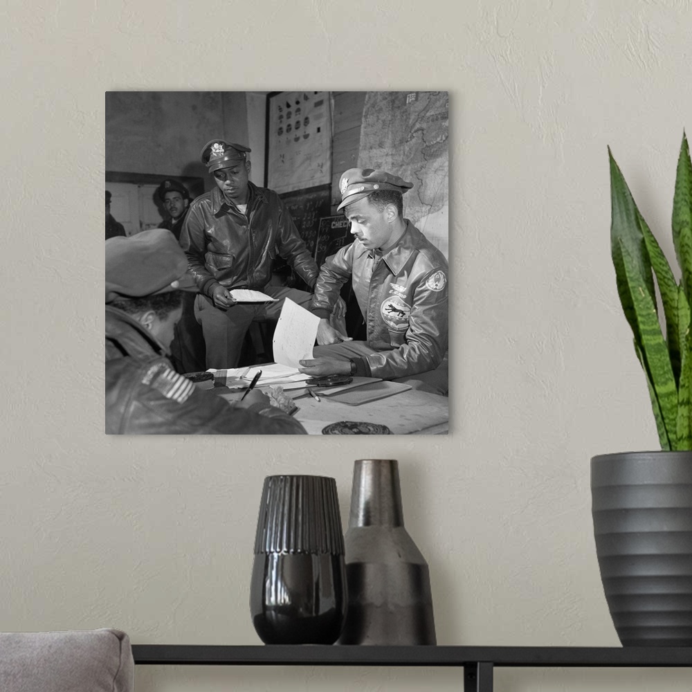 A modern room featuring Tuskegee Airmen Woodrow Crockett (standing) with Group Operations Officer Edward Gleed at Ramitel...