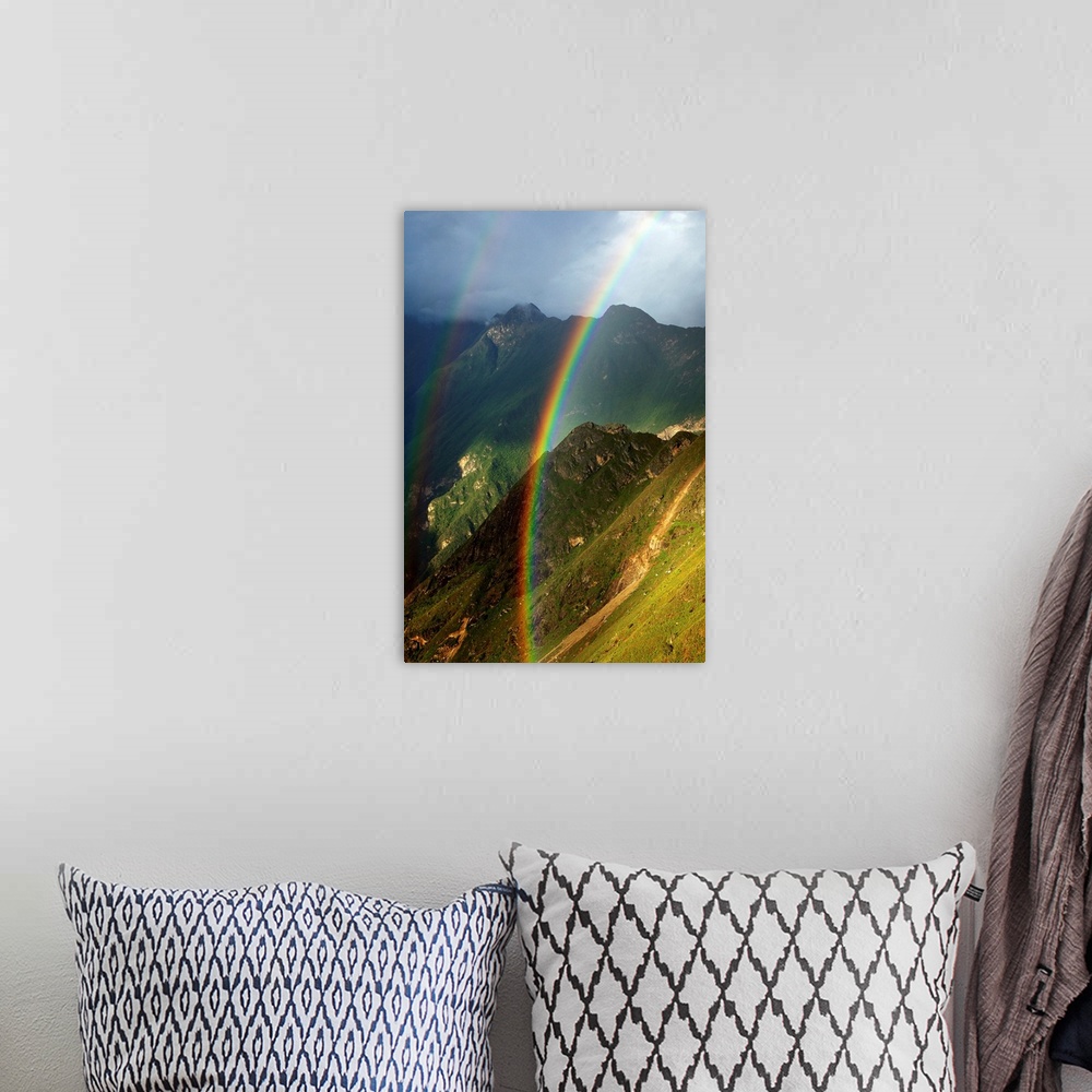 A bohemian room featuring Vertical photograph of a double rainbow over green mountains on a cloudy day.