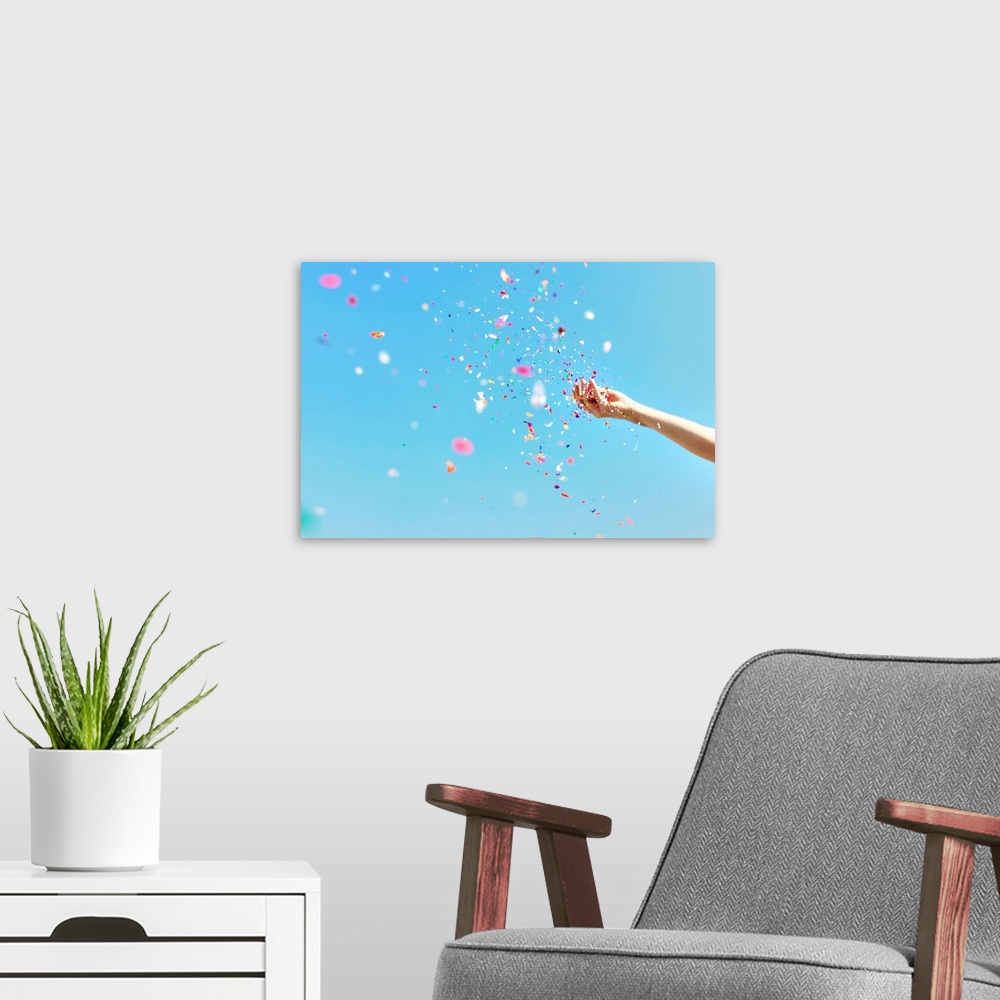 A modern room featuring A bright, airy photograph of a hand throwing colorful confetti against a blue sky.