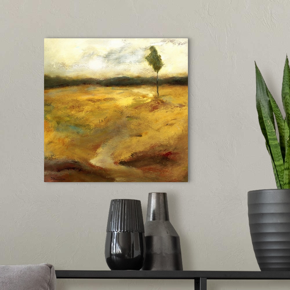 A modern room featuring Contemporary painting of a golden earthy toned landscape with a small lone tree in the distance.