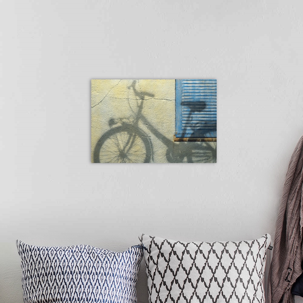 A bohemian room featuring Photograph of the shadow of a bicycle on a wall and blue shutters.