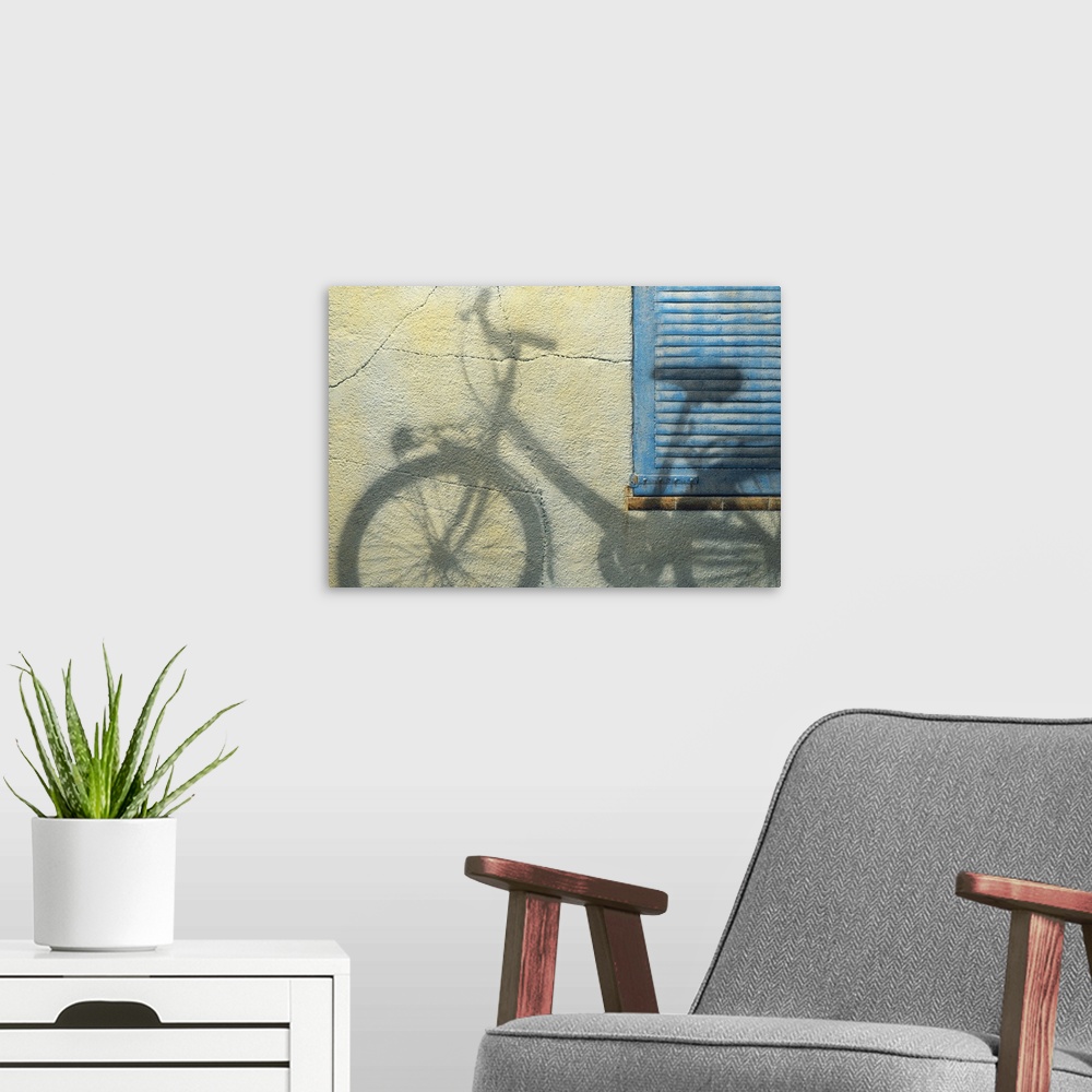 A modern room featuring Photograph of the shadow of a bicycle on a wall and blue shutters.