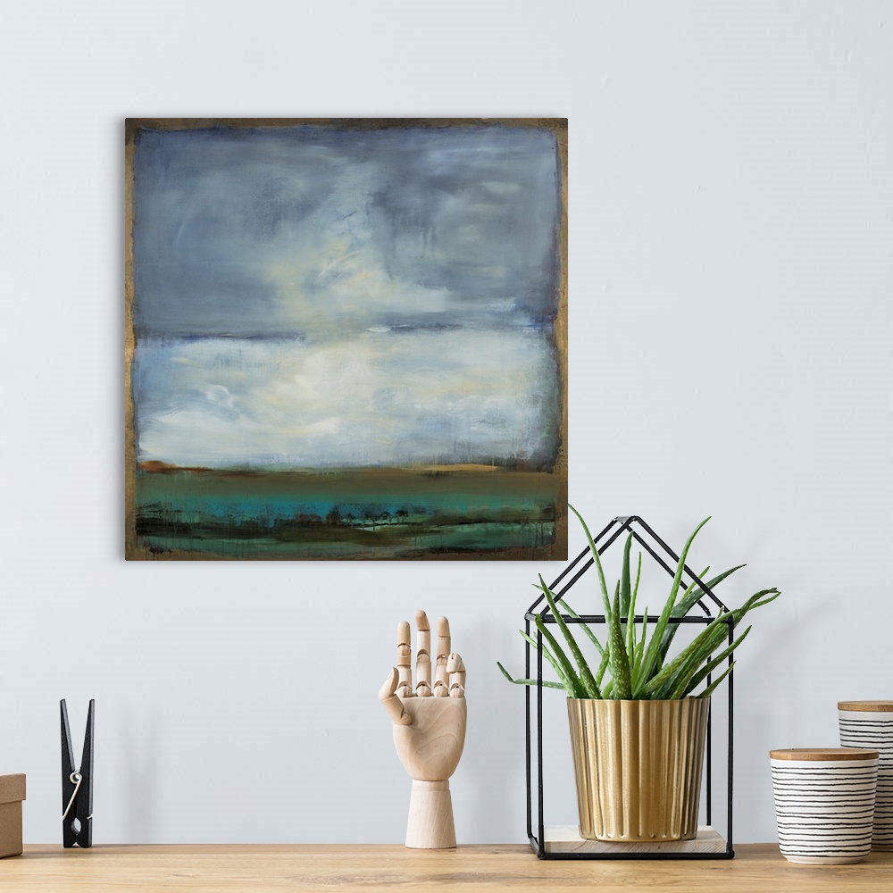 A bohemian room featuring Square abstract painting of a landscape with blue, green, and black hues and a gold boarder and l...
