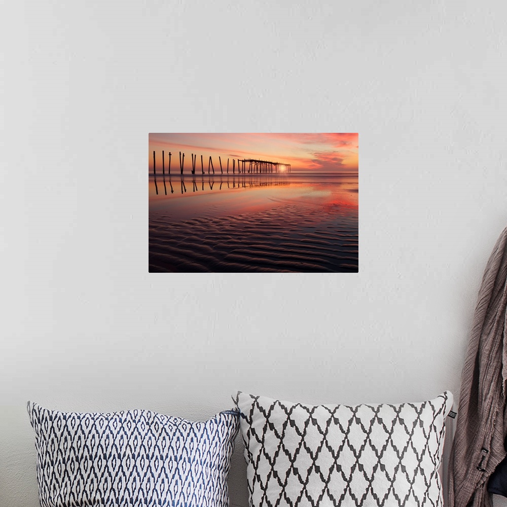 A bohemian room featuring Old wooden pier seen from the beach during a dramatic sunset.