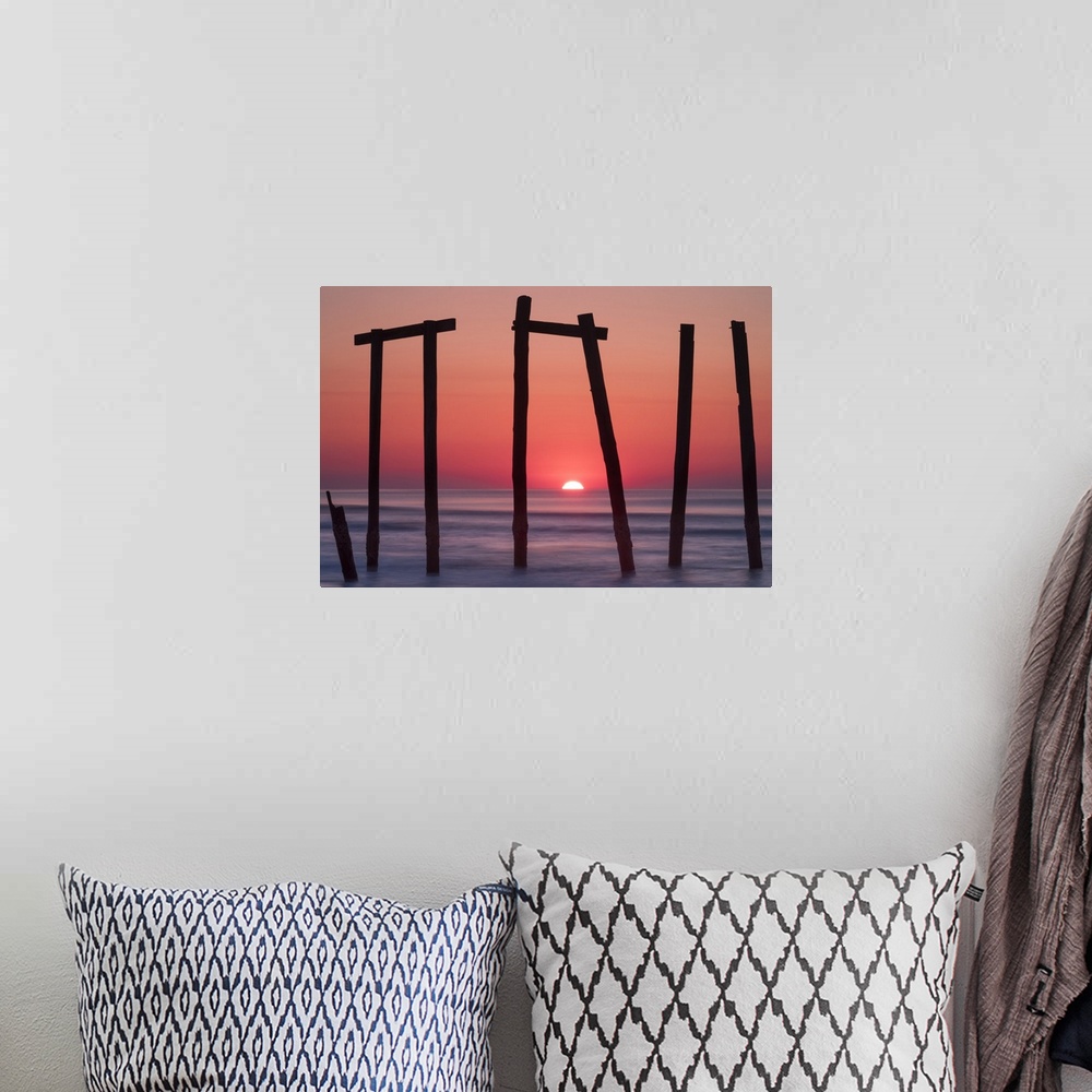 A bohemian room featuring Old pilings from a fishing pier framing a sunrise on the ocean horizon, Ocean City, New Jersey.