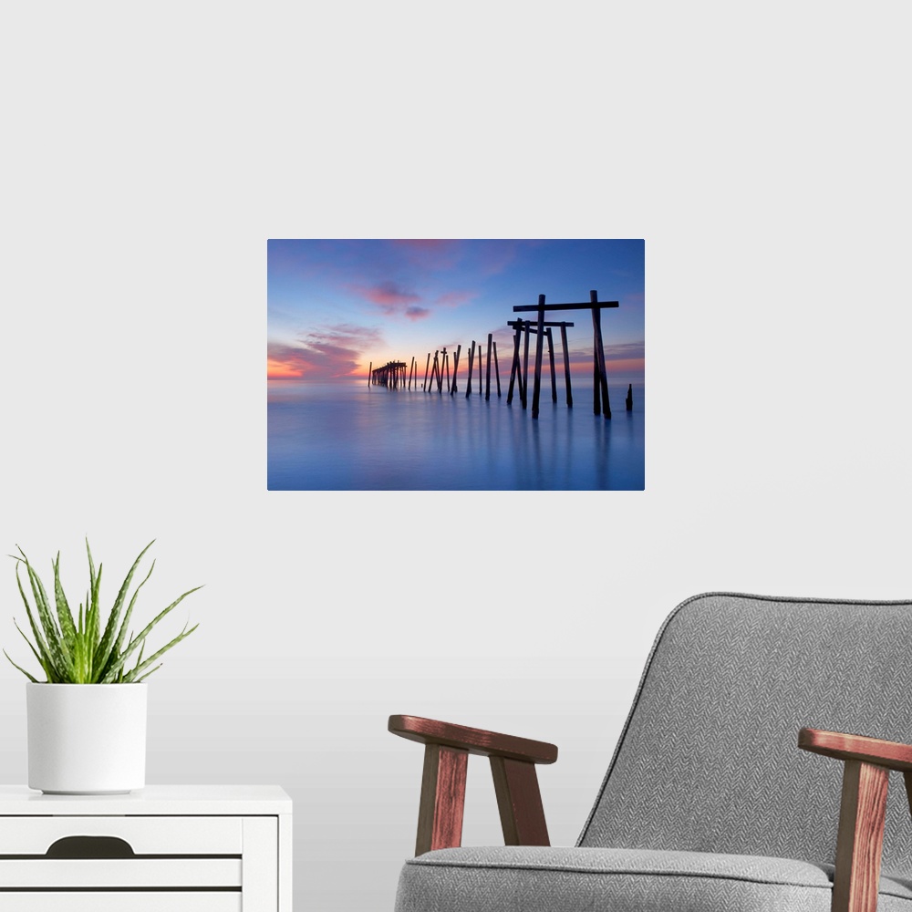 A modern room featuring Old wooden pilings from a long-gone pier in the sea off of Ocean City, New Jersey, at dawn.
