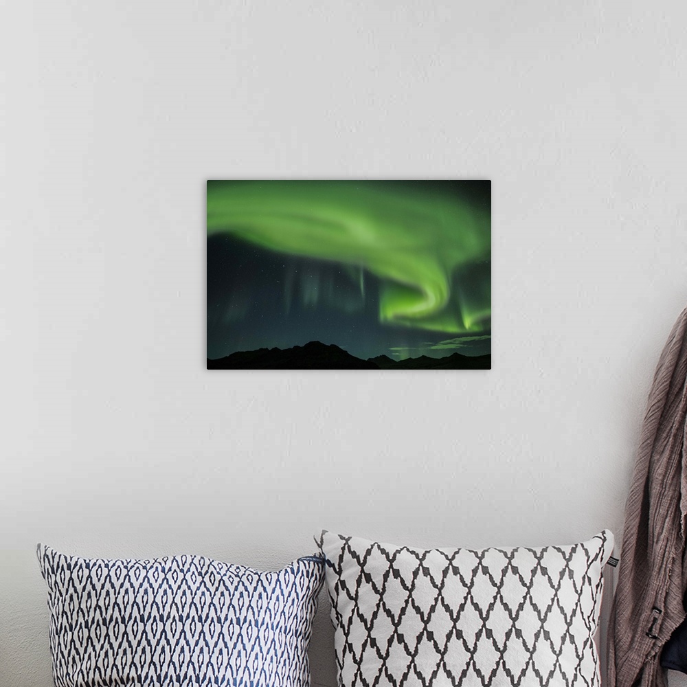 A bohemian room featuring Swirling green Northern Lights in the sky above the South Coast of Iceland.