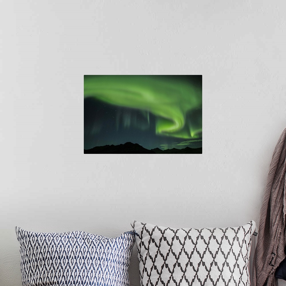 A bohemian room featuring Swirling green Northern Lights in the sky above the South Coast of Iceland.
