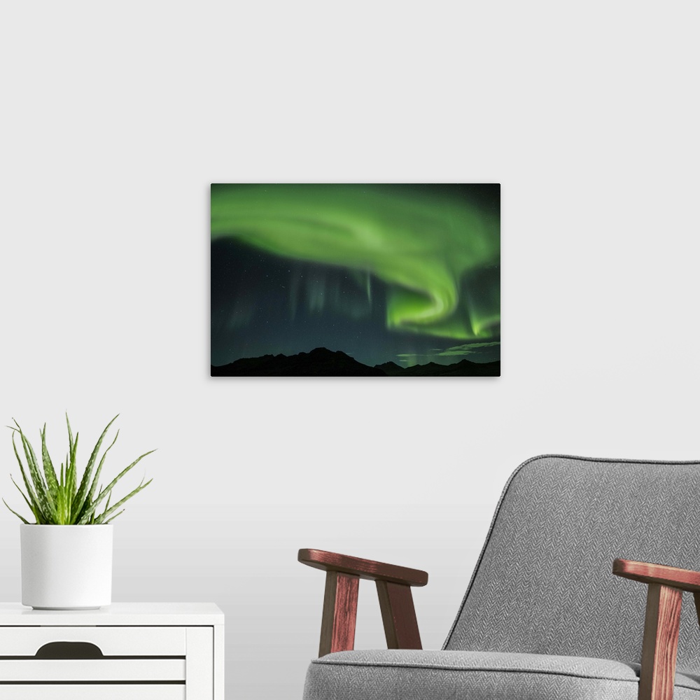 A modern room featuring Swirling green Northern Lights in the sky above the South Coast of Iceland.