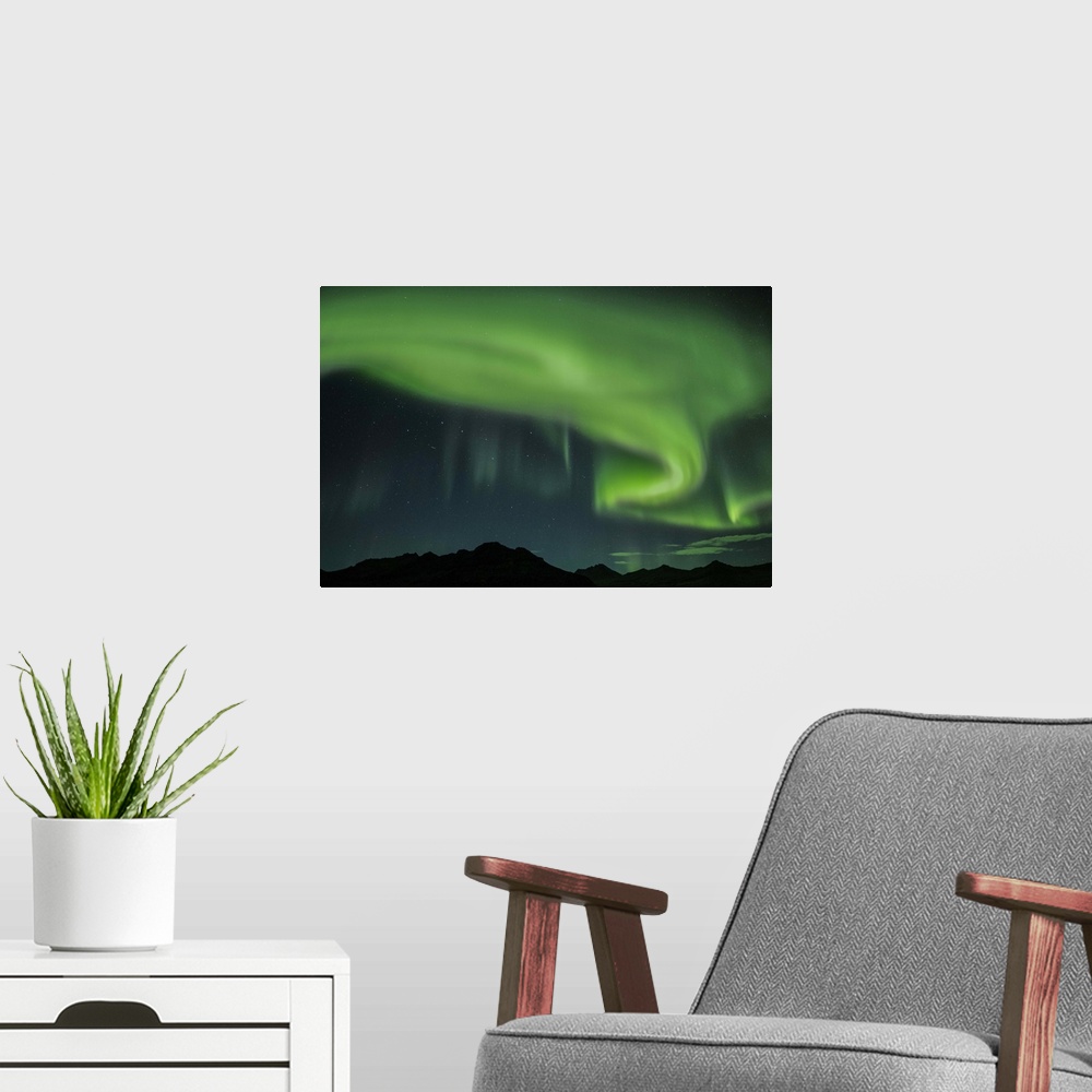 A modern room featuring Swirling green Northern Lights in the sky above the South Coast of Iceland.
