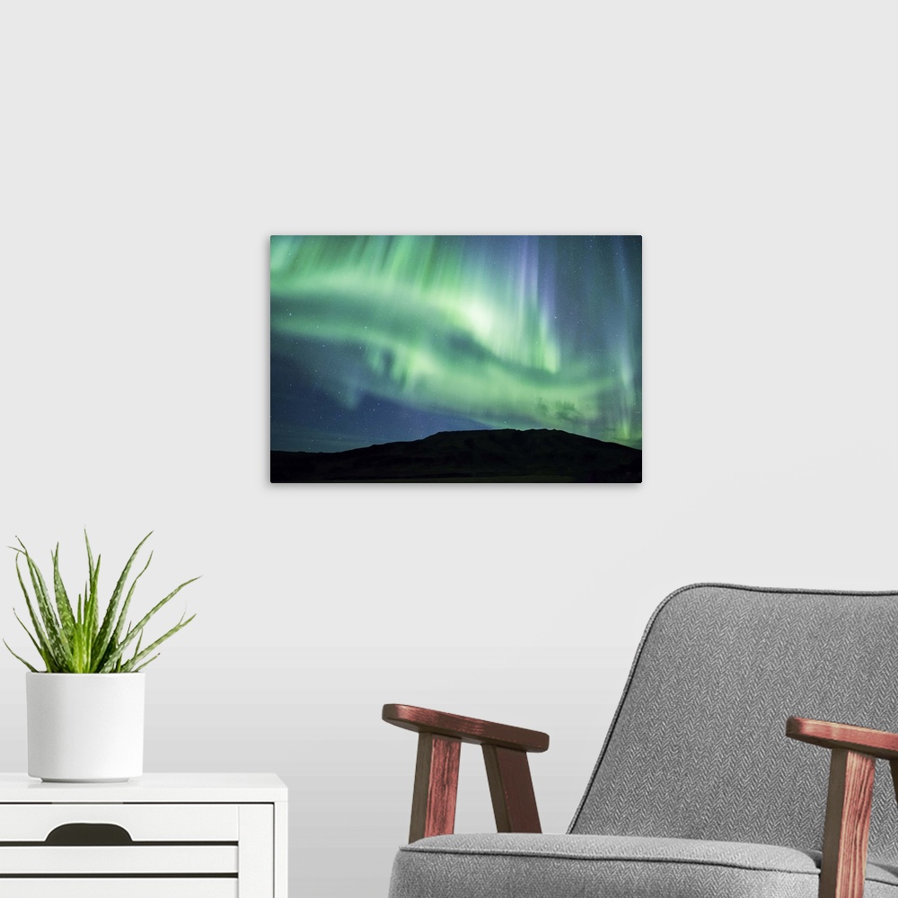A modern room featuring Vivid green and blue Northern Lights in the sky above the South Coast of Iceland.