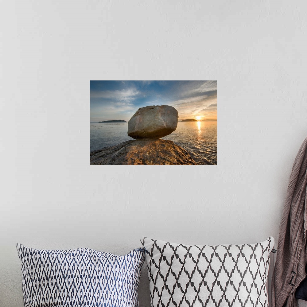A bohemian room featuring A large rock on the beach in Acadia National Park in Maine, with the sun rising in the distance.