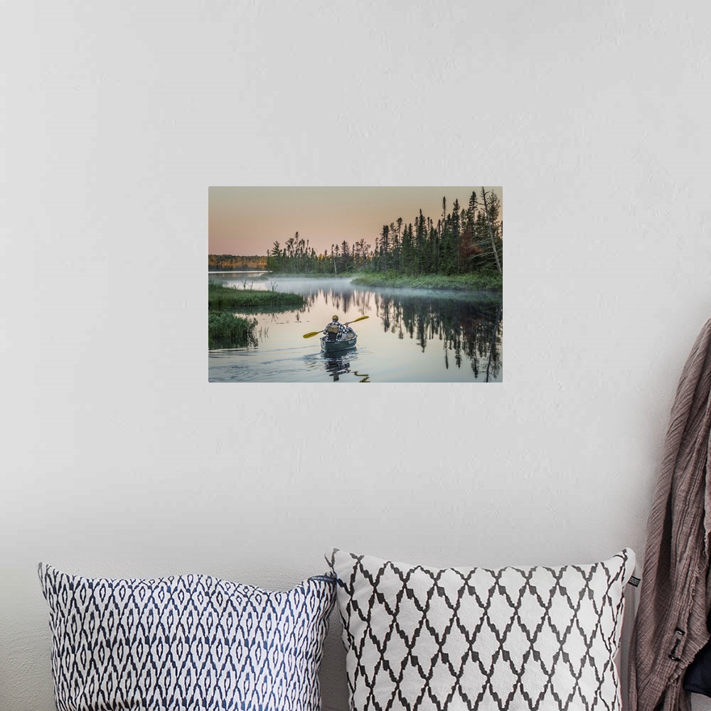 A bohemian room featuring A canoeist paddling in quiet waters in the morning on Madeline Island, Wisconsin.