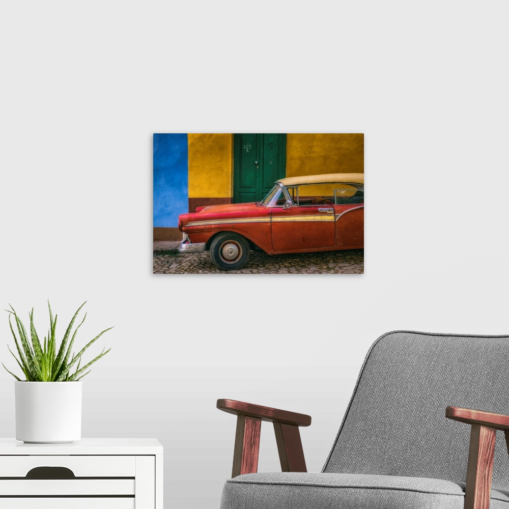 A modern room featuring A bright red vintage car parked against a yellow and blue wall with a green door in the streets o...