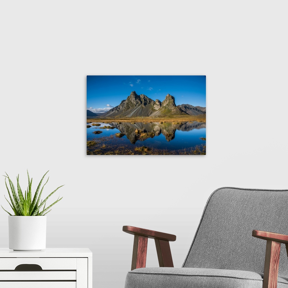 A modern room featuring Rugged mountains in Iceland, reflected in the clear lake below.