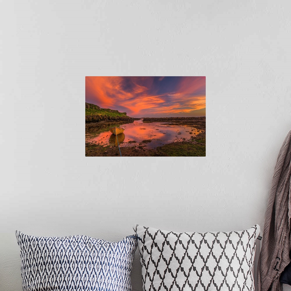 A bohemian room featuring A canoe moored at low tide under vivid sunset clouds in Iceland.