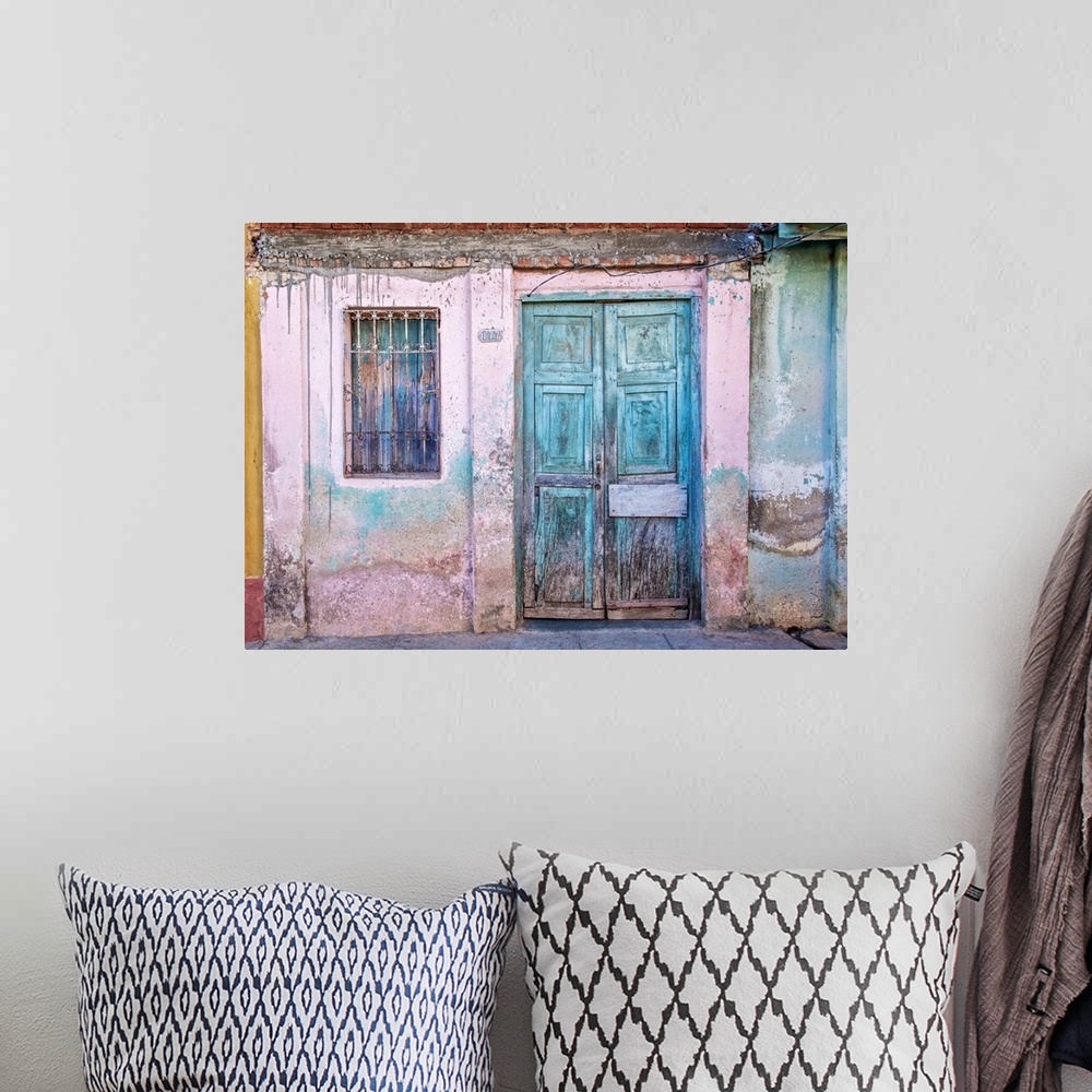 A bohemian room featuring Weathered front of a building with pink paint and blue doors in Havana, Cuba.