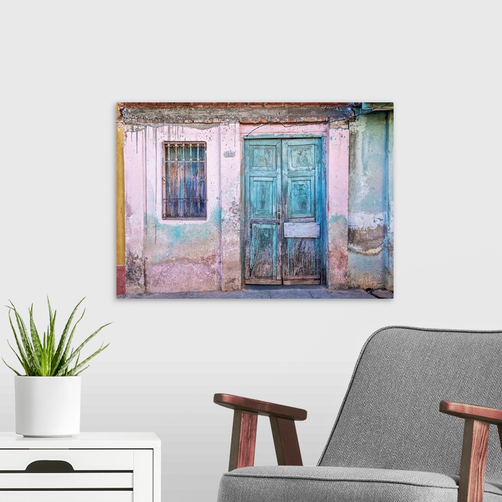 A modern room featuring Weathered front of a building with pink paint and blue doors in Havana, Cuba.