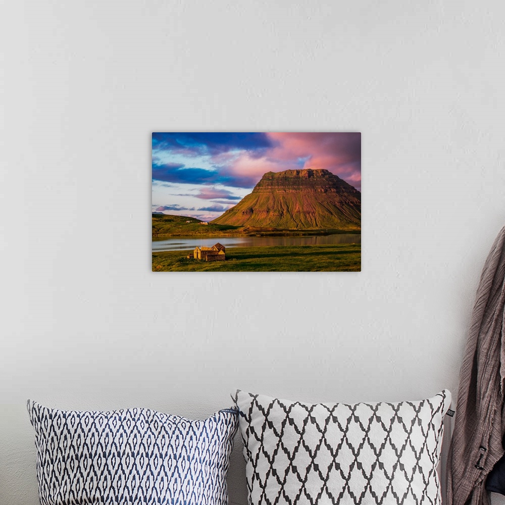 A bohemian room featuring A small house near a mountain with pink clouds at sunset in Iceland.