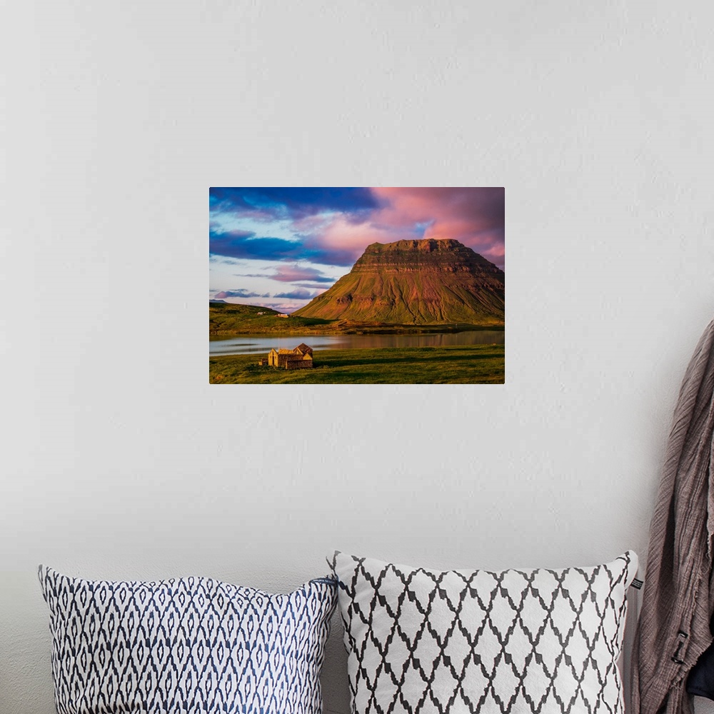 A bohemian room featuring A small house near a mountain with pink clouds at sunset in Iceland.