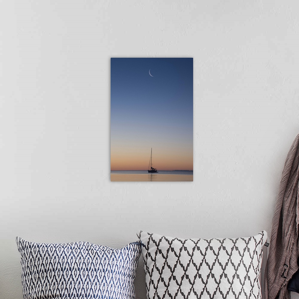 A bohemian room featuring Crescent moon in the sky over a single sailboat on Lake Superior at sunset, Wisconsin.