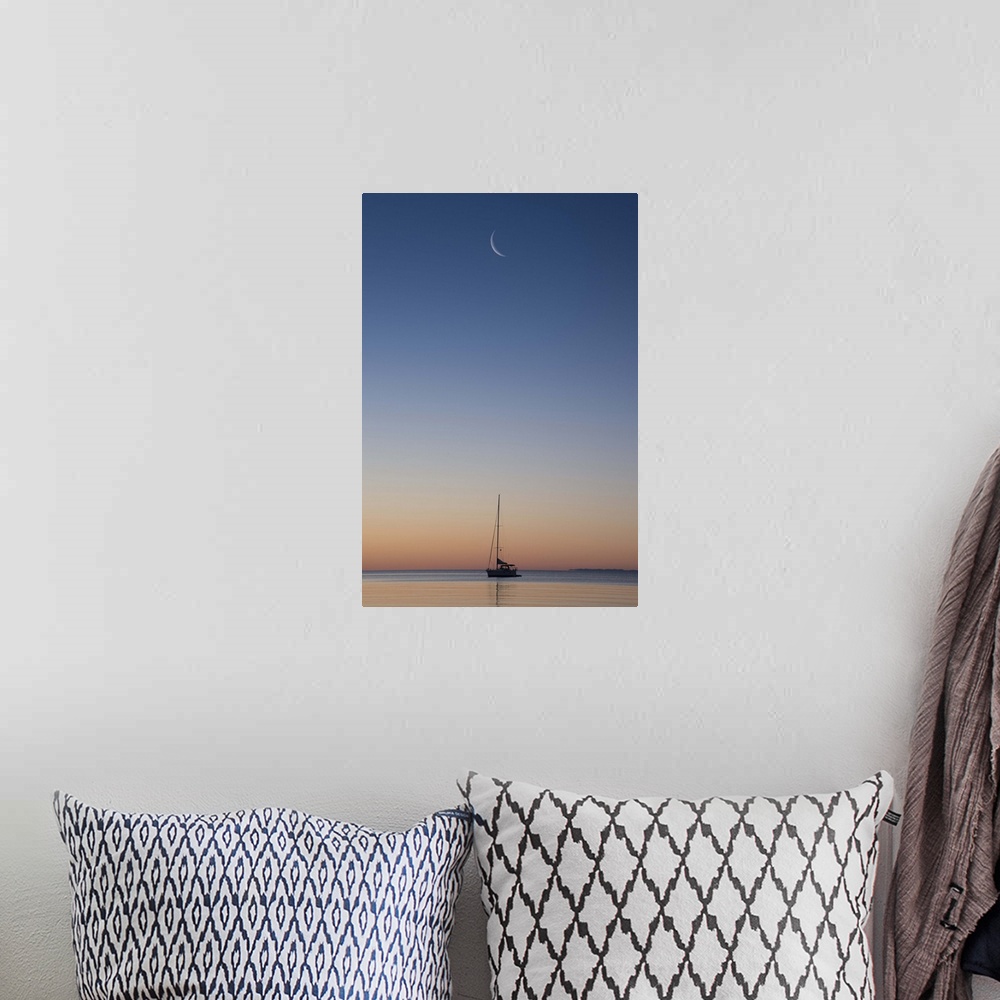 A bohemian room featuring Crescent moon in the sky over a single sailboat on Lake Superior at sunset, Wisconsin.