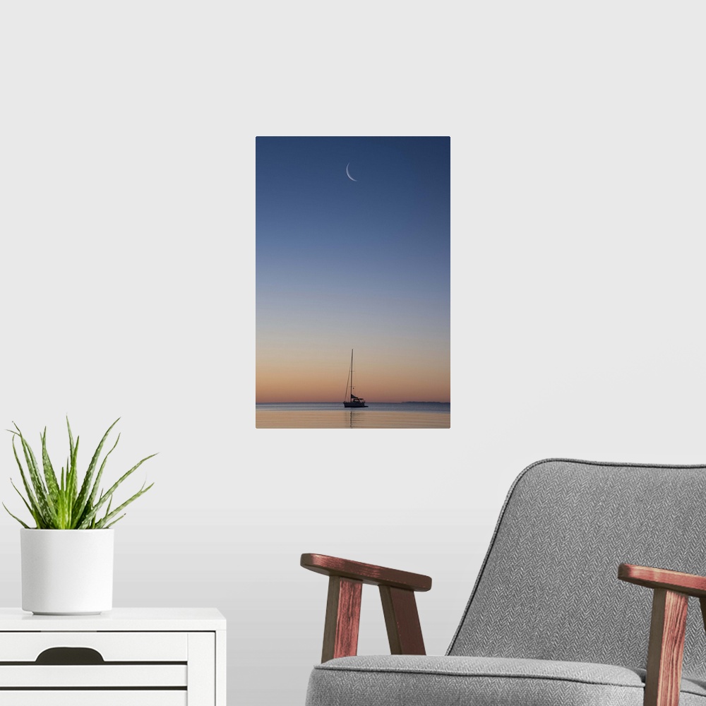 A modern room featuring Crescent moon in the sky over a single sailboat on Lake Superior at sunset, Wisconsin.