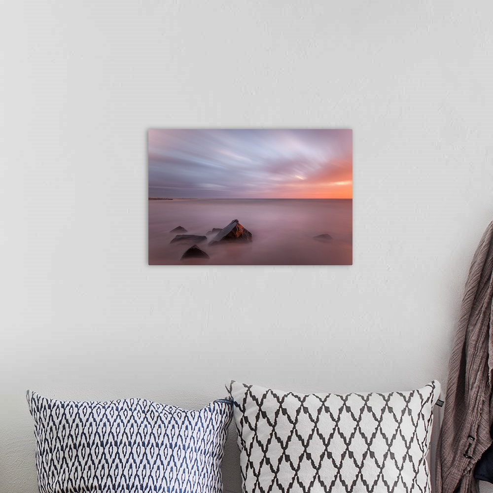 A bohemian room featuring Fading light on small stones in the ocean.