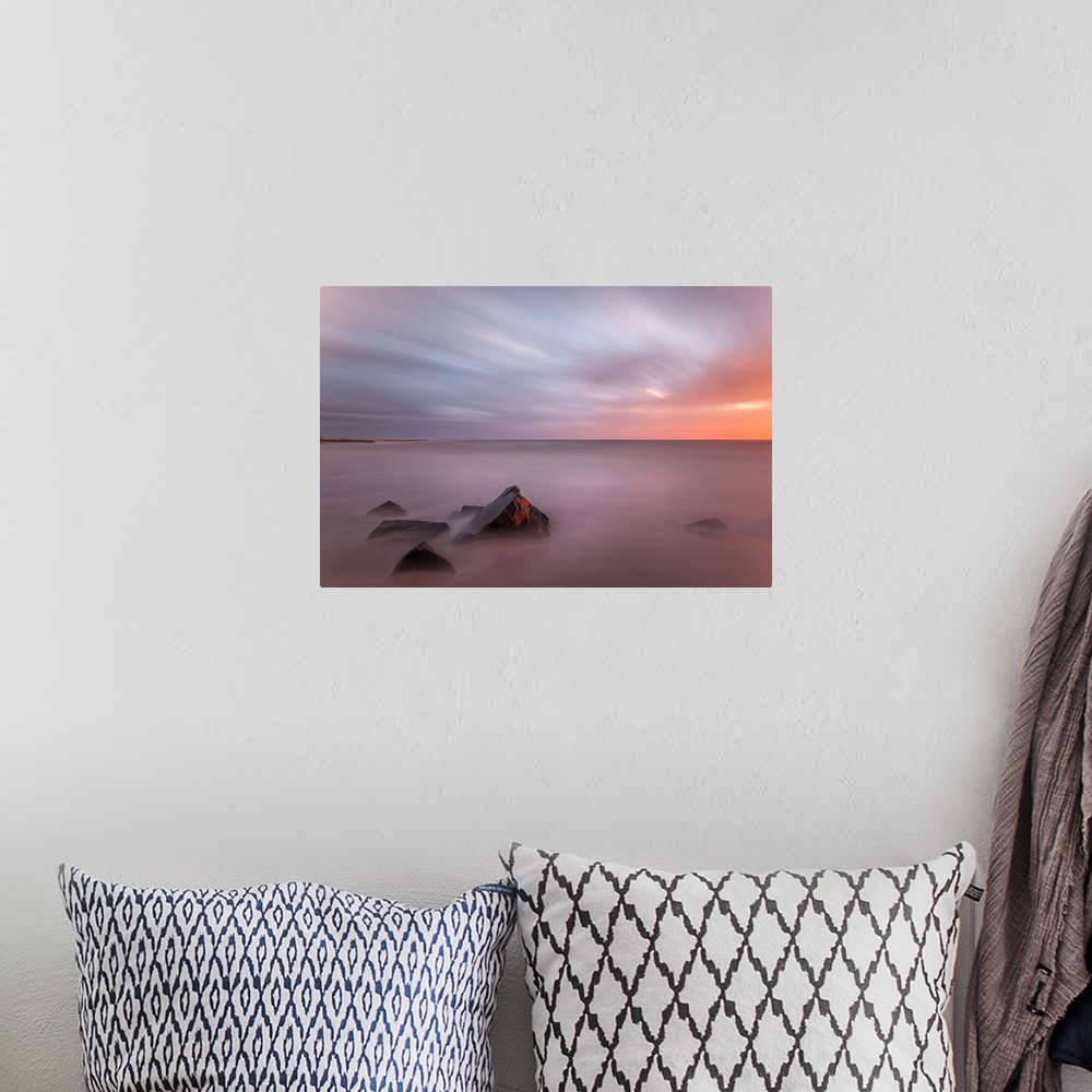 A bohemian room featuring Fading light on small stones in the ocean.