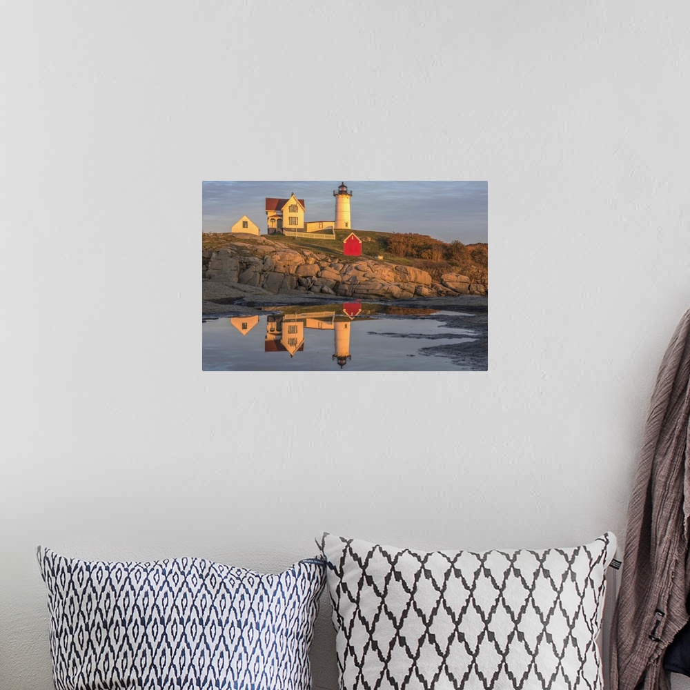 A bohemian room featuring Nubble Lighthouse on a rocky cliff at sunset in Cape Neddick, Maine, reflected in the ocean water...