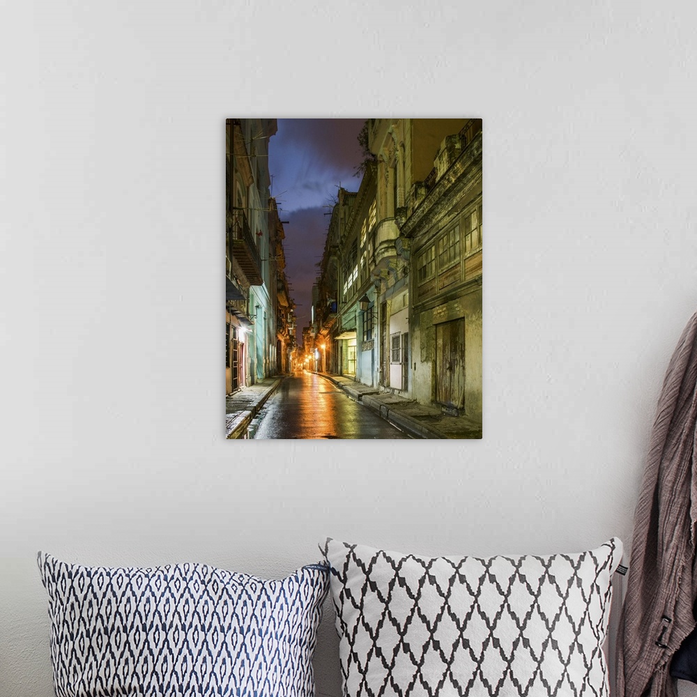 A bohemian room featuring Lights from old buildings reflected on rainy streets in an alley in Havana, Cuba.