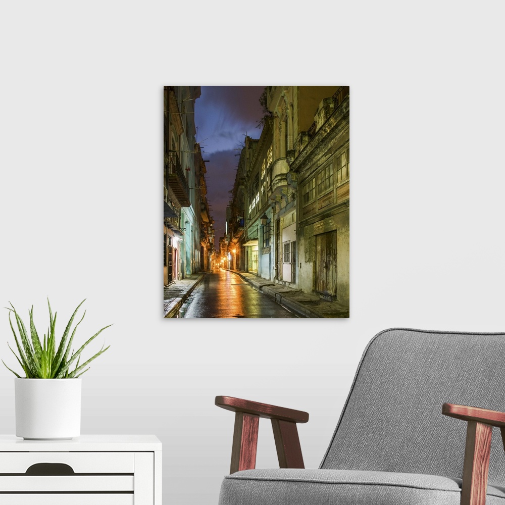 A modern room featuring Lights from old buildings reflected on rainy streets in an alley in Havana, Cuba.