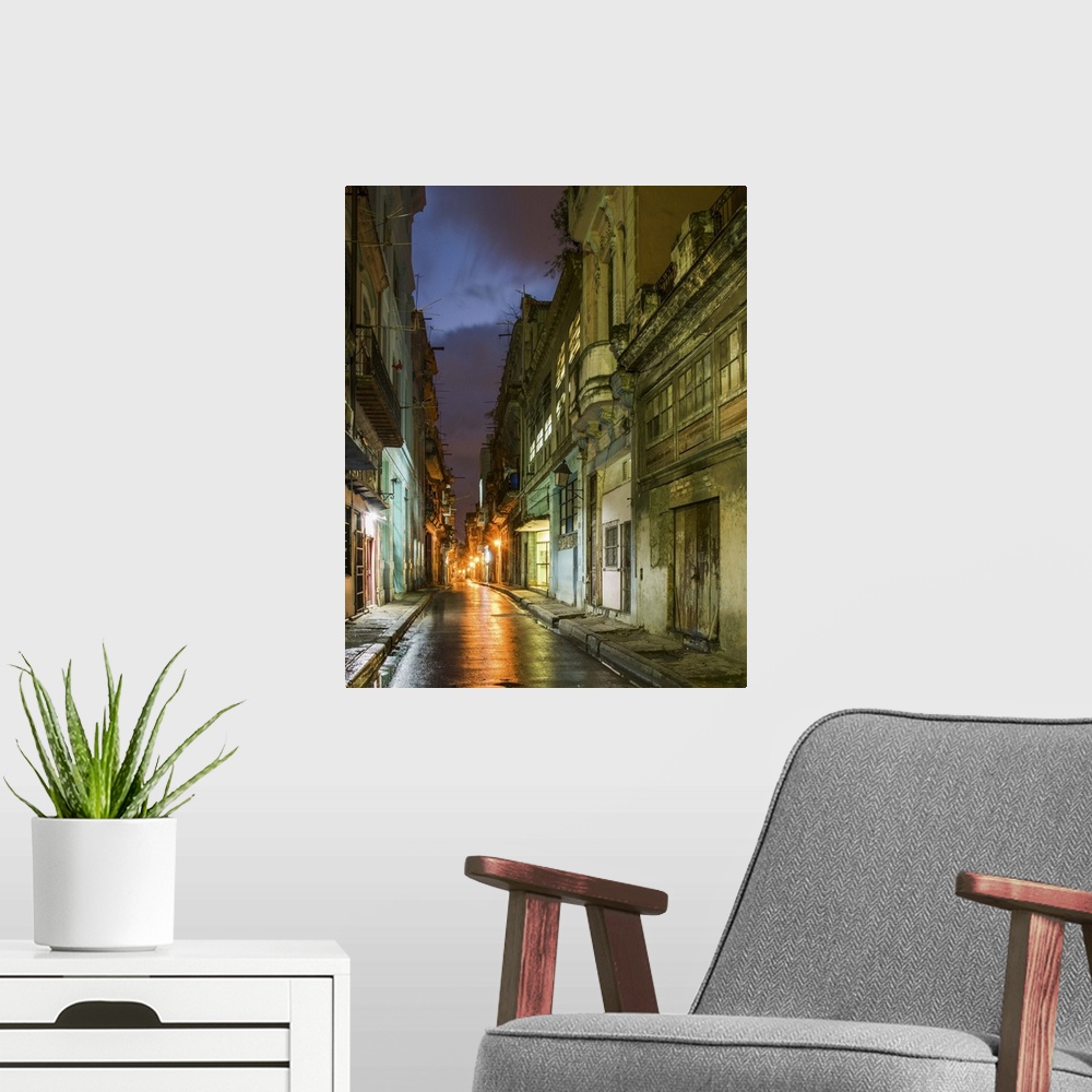 A modern room featuring Lights from old buildings reflected on rainy streets in an alley in Havana, Cuba.