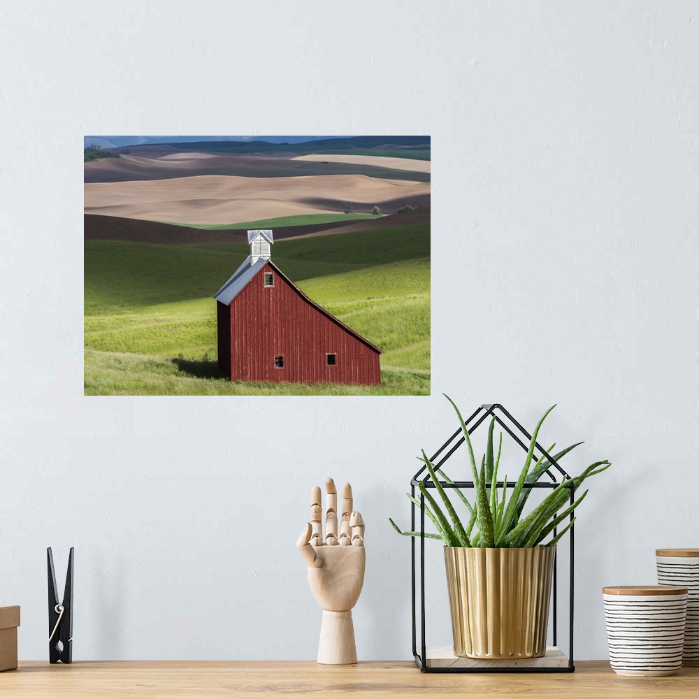 A bohemian room featuring Lone red barn in a green field in the hills of the Idaho countryside.