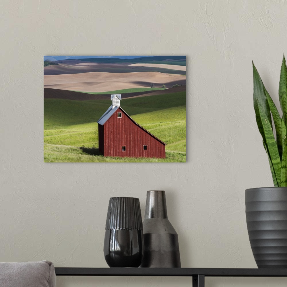 A modern room featuring Lone red barn in a green field in the hills of the Idaho countryside.