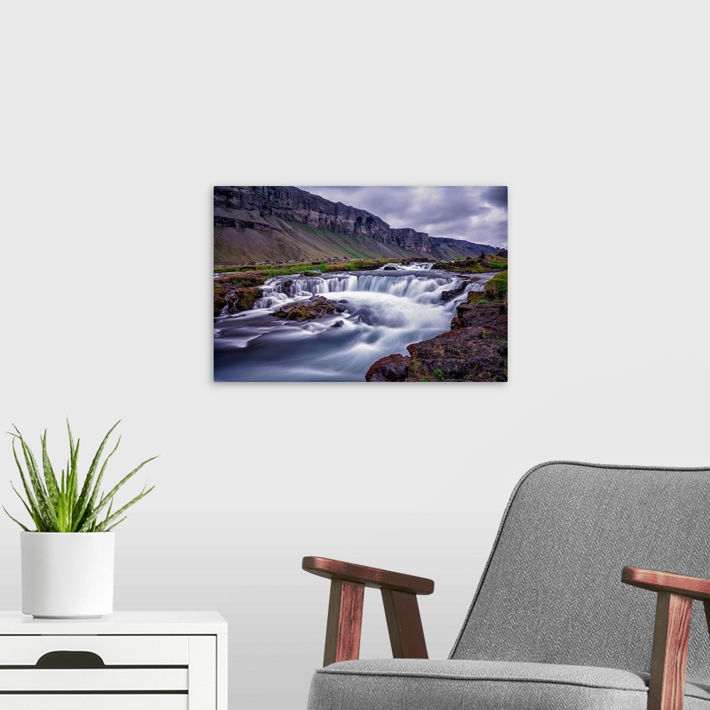 A modern room featuring Rushing water in a freezing river under a cloudy sky in Iceland.