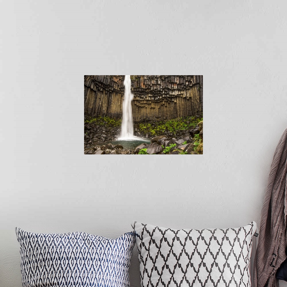 A bohemian room featuring Tall waterfall from a cliff with columnar basalt in Iceland.